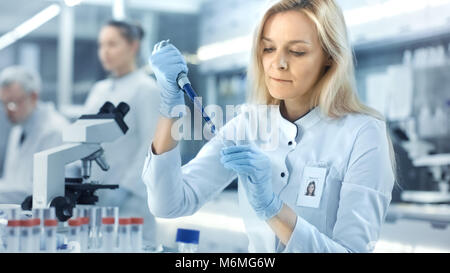 Female Research Scientist Uses Micropipette Filling Test Tubes. Scientist Work in a Big Laboratory/ Research Center. Stock Photo