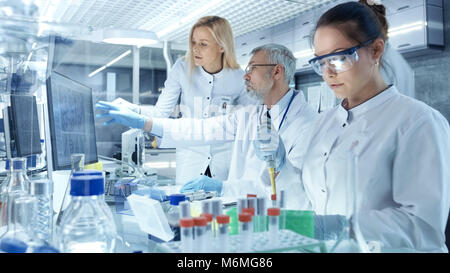 Team of Research Scientists Working With Personal Computer, Analysing Test Trial New Generation Drug Data. They Work in a Modern Laboratory Stock Photo
