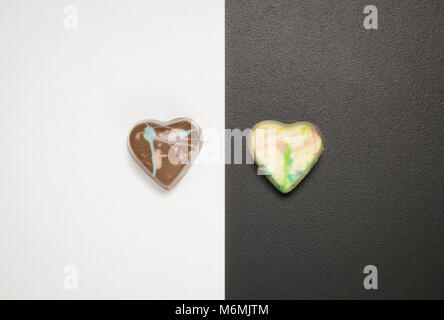 Flat lay of heart shape pralines on black and white background. Minimal sweet and love concepts. Stock Photo