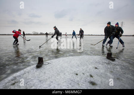 People playing ice hockey and skating on the Cambridgeshire Fens near Peterborough on Friday morning March 2nd after the flooded fields froze over in the current cold weather, its the first time in 6 years they the Fens have frozen over.  Skaters have been flocking to the frozen Cambridgeshire Fens today (Fri) after the Beast from the East gave them the rare chance to enjoy the ancient sport for the first time in SIX YEARS.  Shallow waters in the Fens have been turned into an enormous natural ice rink and it is now a skater's paradise.  Skaters Stock Photo