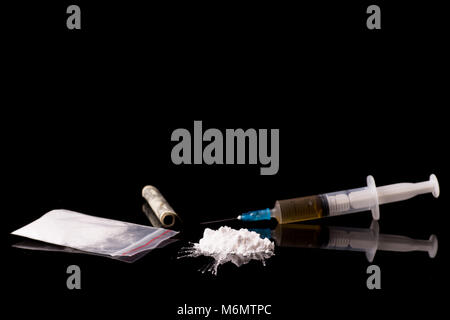 cocaine, Herion or other illegal drugs that are sniffed by means of a tube or injected with a syringe isolated on black glossy background Stock Photo