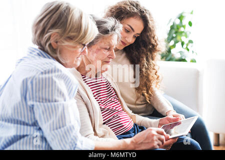 A teenage girl, mother and grandmother with tablet at home. Stock Photo