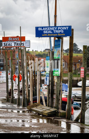 Seal trip signs on the dockside at Blakeney Harbour, Norfolk, UK. Stock Photo