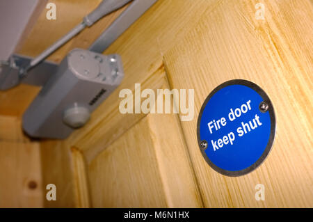 A Fire door keep shut sign on a wooden door Stock Photo