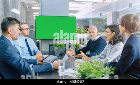 Diverse Group of Successful Business People in the Conference Room with  Green Screen Chroma Key TV on the Wall. They Work on a Company's Growth Stock Photo