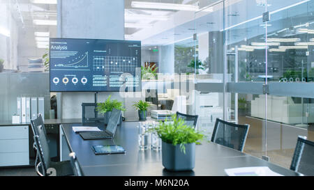 Modern Empty Meeting Room with Big Conference Table with Various Documents and Laptops on it, on the Wall Big TV Showing Company's Growth, Statistics  Stock Photo