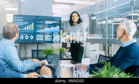 Chief Female Executive Gives a Report/ Presentation to Her Colleagues in the Meeting Room, She Shows Graphics, Pie Charts and Graphs Stock Photo