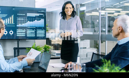 Beautiful Businesswoman Gives Report/ Presentation to Her Business Colleagues in the Conference Room, She Shows Graphics, Pie Charts and Graphs Stock Photo