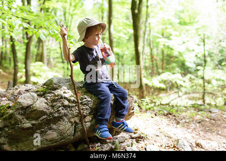 Little blond boy wearing a hat taking a break while hiking, drinking from bottle, Slovenia, Europe Stock Photo