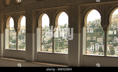 GRANADA SPAIN - OCTOBER 10 10 2010: A view to Granada through a window decorated with calligraphy and oriental ornaments in the palace of Alhambra Stock Photo