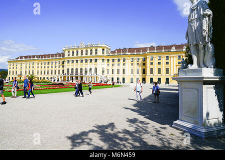 VIENNA,AUSTRIA - SEPTEMBER 4 2017; Tourists arriving ai morning walking past lawn and formal gardens in front baroque architectural detail of the Scho