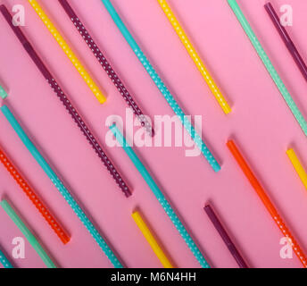 colorful plastic tube with white polka dots for drinks scattered on a pink background Stock Photo