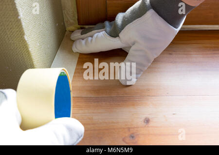 Painter worker protecting window sills with masking tape before painting at home improvement work Stock Photo