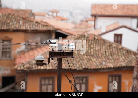 Old electric linear insulator on pole and old style Turkish homes in background Stock Photo