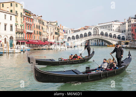 Two gondolas on the Grand Canal in winter with rooftop snow, Rialto Bridge,  San Polo, Venice, Italy. One boat has an African couple, the other a Cauc Stock Photo