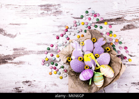 Easter gingerbread cookies and colorful candies on wooden table. Rabbits and eggs. Greeting card. View from above.Copy space. Stock Photo