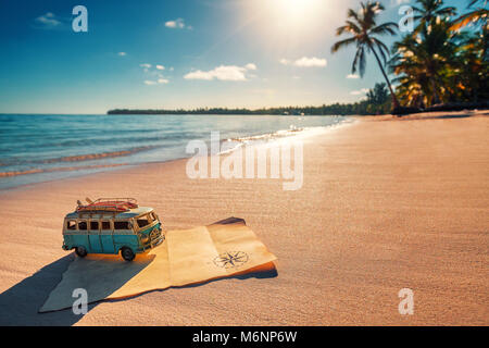 Travel vintage miniature van and old treasure map on the tropical beach at sunrise, travel concept.Travel cocept. Stock Photo