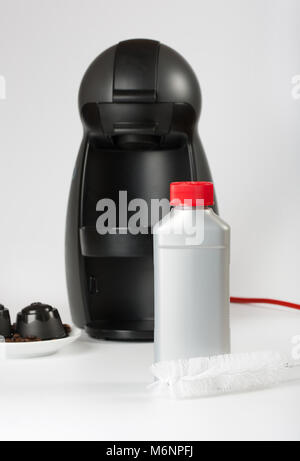 Coffee machine liquid limescale remover. Coffee capsules and coffee machine in the background. Closeup Stock Photo