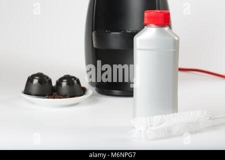 Coffee machine liquid limescale remover. Coffee capsules and coffee machine in the background. Closeup Stock Photo