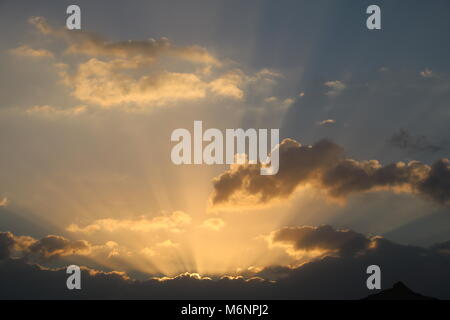 golden rays of early morning sunrise light bursting through clouds Stock Photo