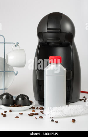 Coffee machine liquid limescale remover. Coffee capsules and coffee machine in the background. Closeup Stock Photo