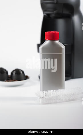 Coffee machine liquid limescale remover. Coffee capsules and coffee machine in the background. Closeup Stock Photo