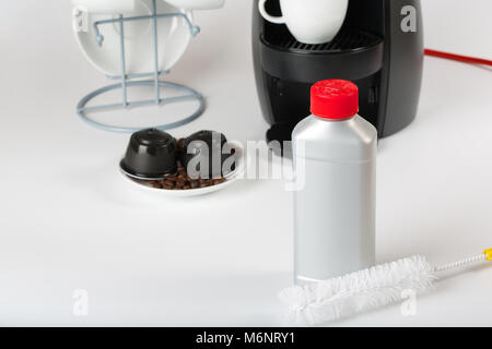 Coffee machine liquid limescale remover. Coffee capsules and coffee machine in the background. Closeup Stock Photo