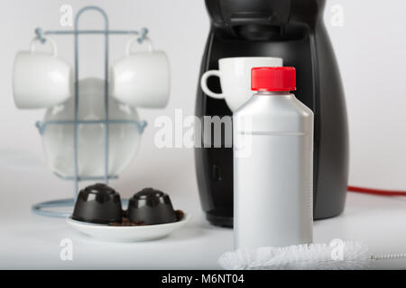 Coffee machine liquid limescale remover. Coffee capsules and coffee machine in the background. Closeup Stock Photo