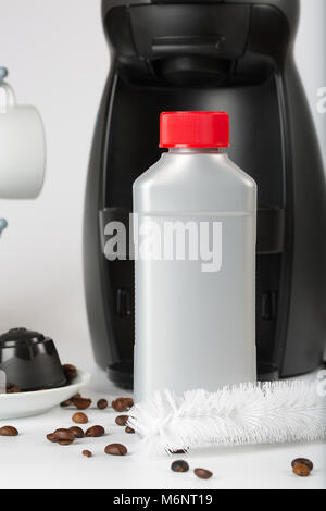 Coffee machine liquid limescale remover. Coffee capsules and coffee machine in the background. Closeup Stock Photo