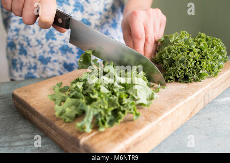 Close Up Of Woman Preparing Kale On Chopping Board Stock Photo