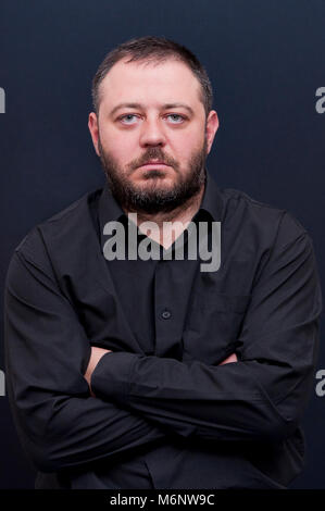 Portrait of serious, severe, grave, strong, young, bearded hidden hands man with black shirt Stock Photo