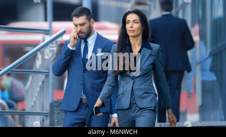 Male and Female Business People Walking Down the Street in the Business District. Stock Photo