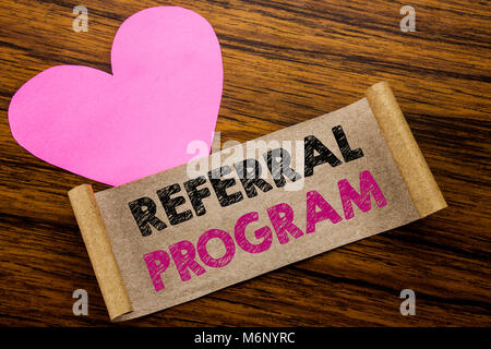 Writing text showing Referral Program. Business concept for Refer Marketing  written on sticky note paper, wooden background. With pink heart meaning  Stock Photo