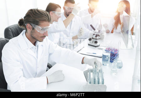 Scientists working with a microscope and make notes in the workp Stock Photo