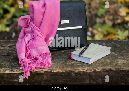women's accessories - leather black bag, neckerchief and notebook on dark wooden surface Stock Photo