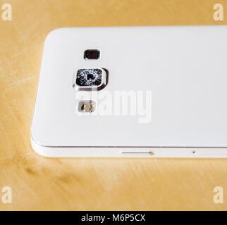 Close up of a white mobile phone with damaged/  cracked/ broken/ shattered protective camera lens glass - with copy space Stock Photo