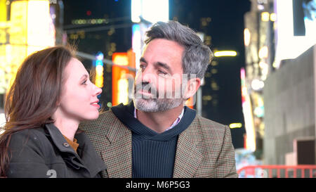 Young romantic happy couple gazing into each others eyes on date night in Times Square, New York City, Manhattan. Attractive hipster style adults lost Stock Photo