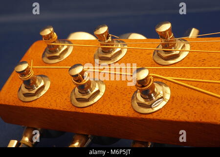 Macro wood acoustic guitar head with six strings and tuning knobs. Stock Photo