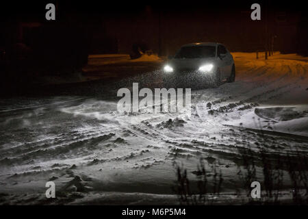 A car driving along a road covered with snow in Redditch, UK Stock Photo