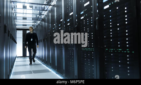 IT Engineer Holding Notebook and Walking Through Data Center Full of Working Rack Servers. Stock Photo