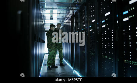 In Data Center Two Military Men Work with Open Server Rack Cabinet. One Holds Military Edition Laptop. Stock Photo