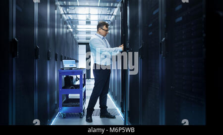 IT Engineer Installing Hard Drives into Working Rack Server. He's Working in Data Center. Stock Photo