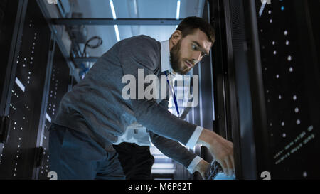 Male Server Engineer Takes Out Components from Server Rack Cabinet. He is in Big Data Center. Stock Photo