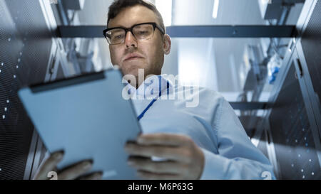 Server Technician Working in Data Center. They Walk Through Working Rows of Server Racks. Stock Photo