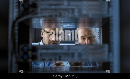 Two Server Engineers Install Hardware in Server Rack. They Work in Big Modern Data Center. Stock Photo