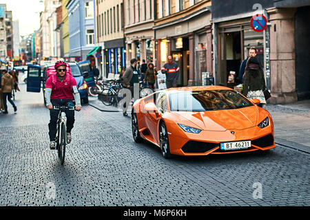 Orange Lamborghini Huracan LP 580-2 Spyder car released circa 2016 in Italy parked on the street with a bicycle courier passing by. Stock Photo