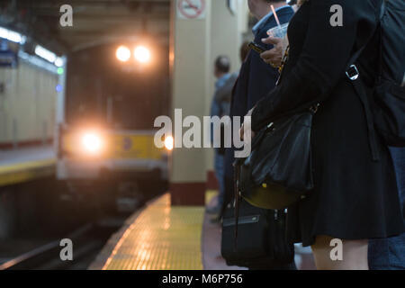 Passengers wait for railroad train to arrive at station platform to board for commute home from New York City in evening rush hour Stock Photo