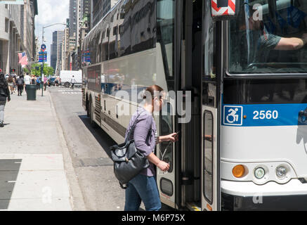 New York City, Circa 2017: Woman enters MTA Bus on Manhattan 5th avenue during day time commute. People use public transportation to navigate through  Stock Photo