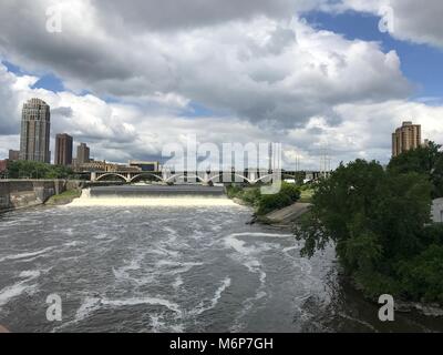 Establishing shot view of Minneapolis skyline on summer day overlooking flowing Mississippi River Stock Photo