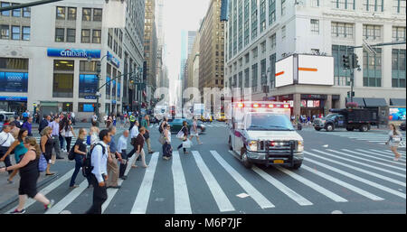 New York City, Circa 2017: NYC ambulance crosses busy Manhattan intersection and crosswalk to ugent medical emergency for first aid assistance during  Stock Photo